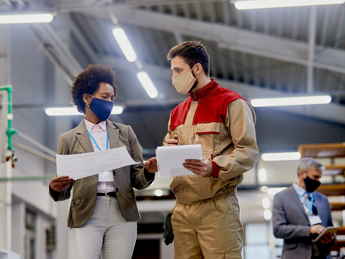 An investigator interviewing a machine operator on the shop floor